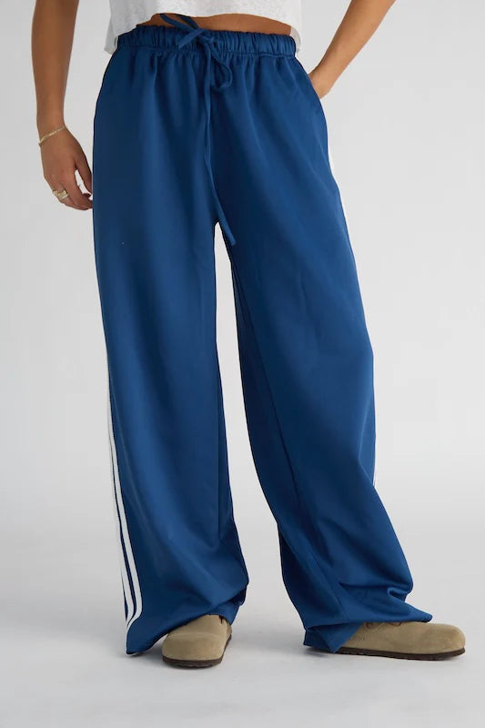 Blue wide-leg pants with white stripes on a plain background