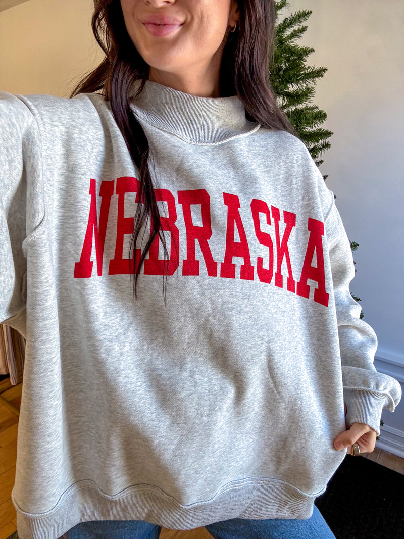 Person wearing a gray sweatshirt with 'NEBRASKA' printed in red.