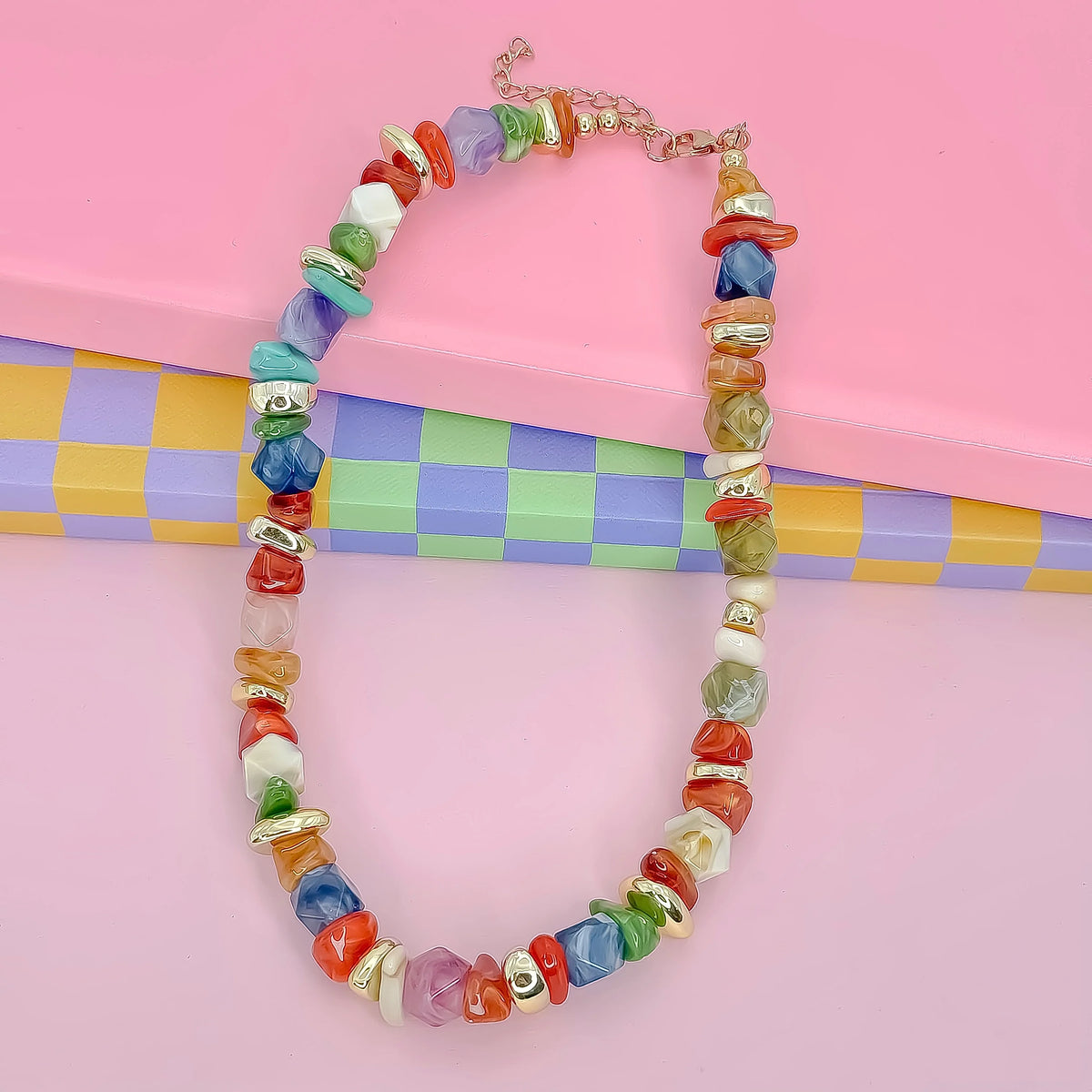 Colorful beaded necklace on a pink background with a checkered pattern