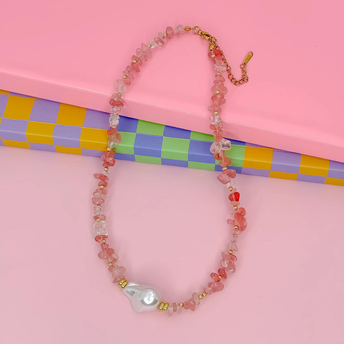 Beaded necklace with a large pearl pendant on a pink background with a colorful checkered pattern.