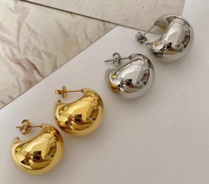 Gold and silver hoop earrings on a light surface