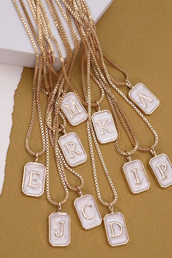 A collection of monogram initial necklaces in gold tone, each with a different letter pendant.